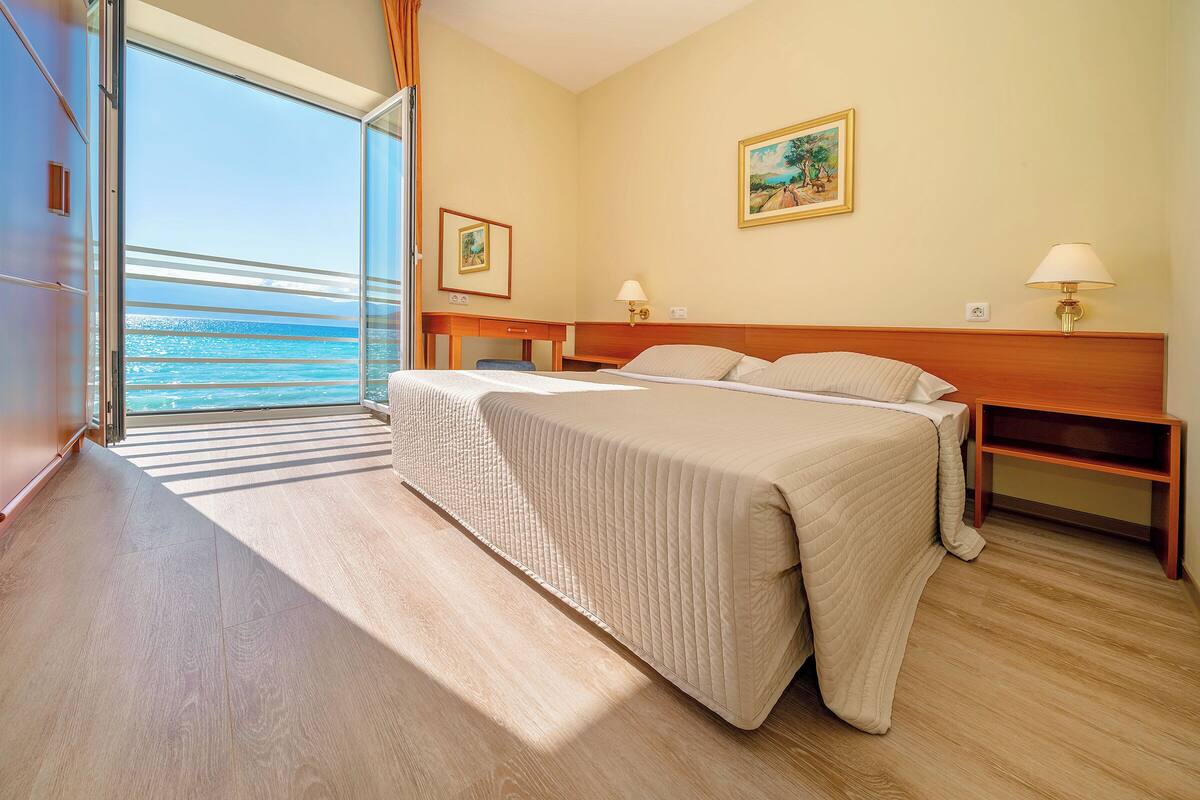 A hotel room with a large bed, a desk, and a view of the ocean.
