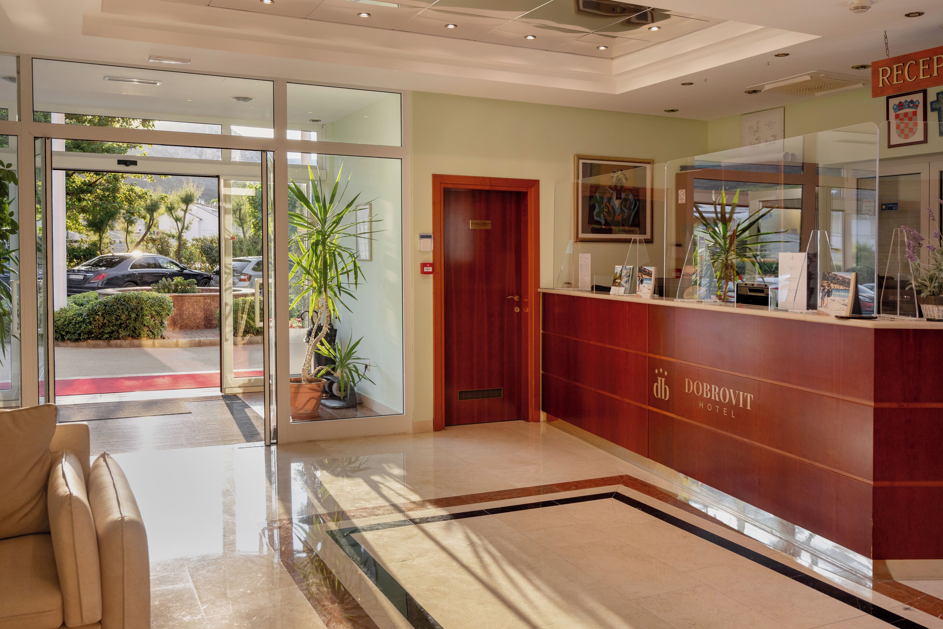 A reception area with a glass door leading outside, a reception desk, and a reception sign.