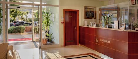 A reception area with a glass door leading outside, a reception desk, and a reception sign.