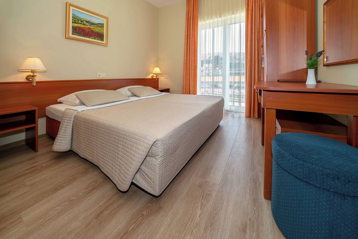 A hotel room with a bed, bedside tables, a desk, and a chair.
