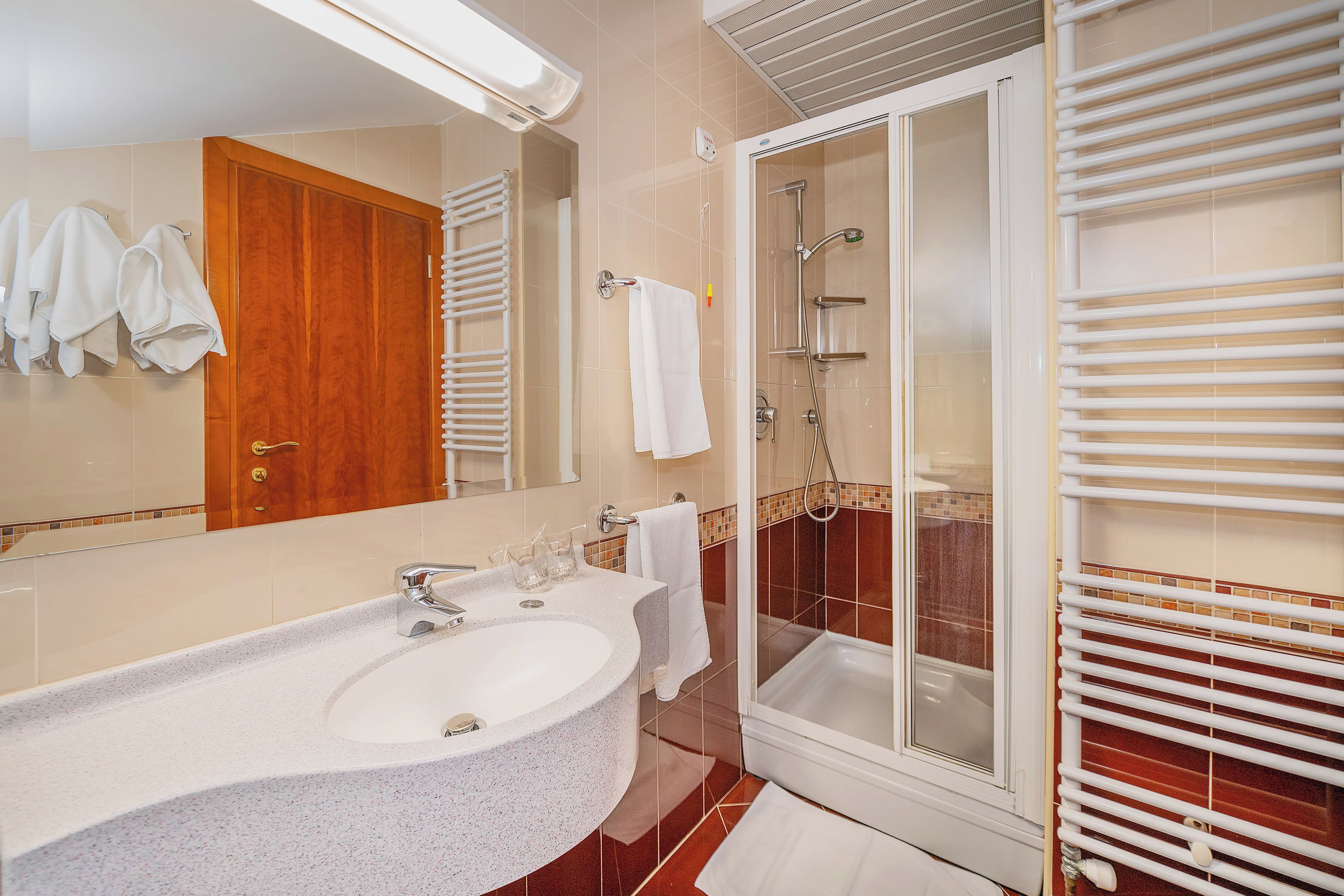 A bathroom with a double sink, a glass-enclosed shower, and a wooden door.