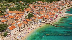 Vista aérea de un pueblo costero con playa, edificios y una torre.