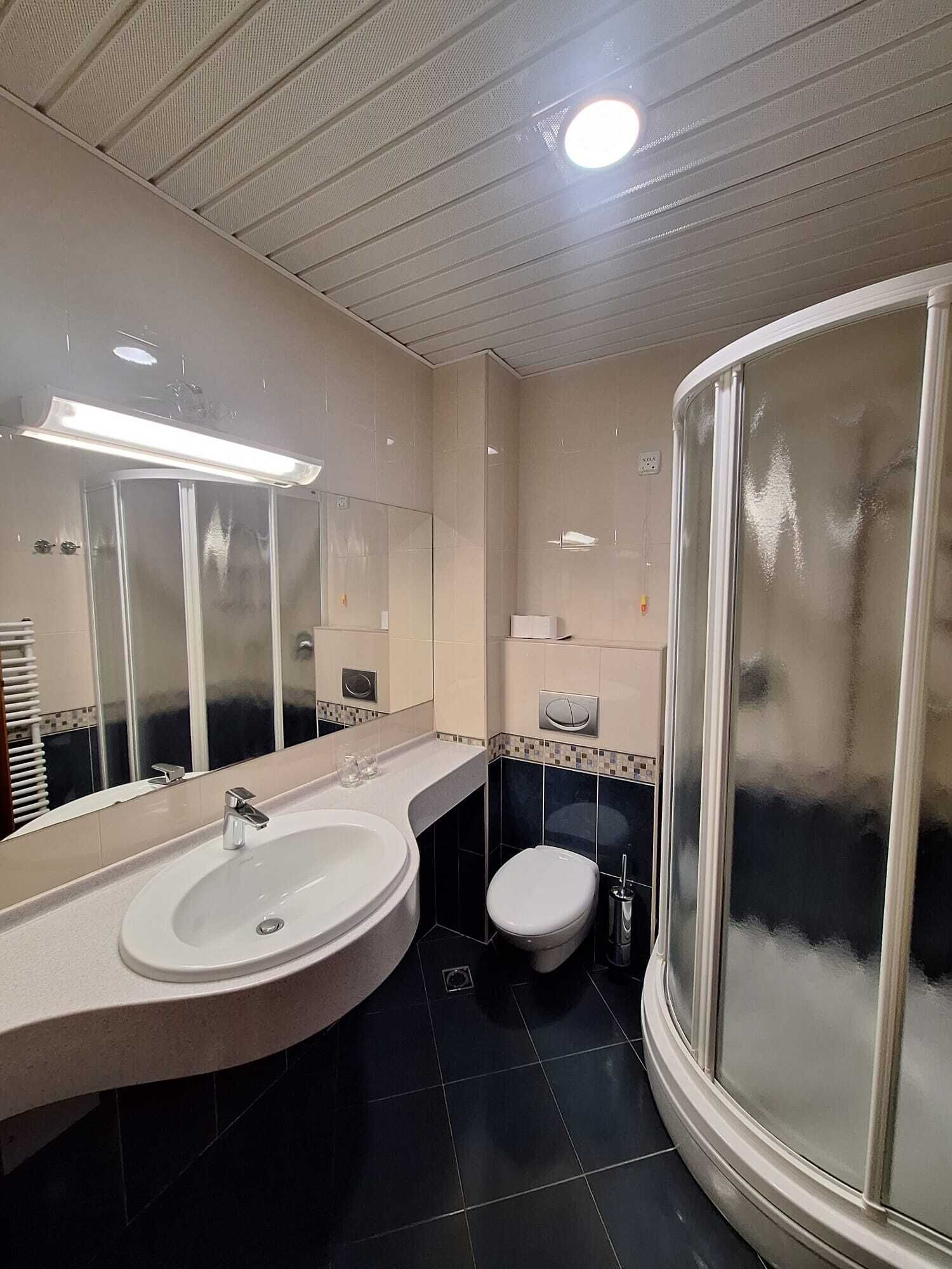 Une salle de bain moderne avec un lavabo aux lignes courbes, des toilettes et une douche à parois de verre.