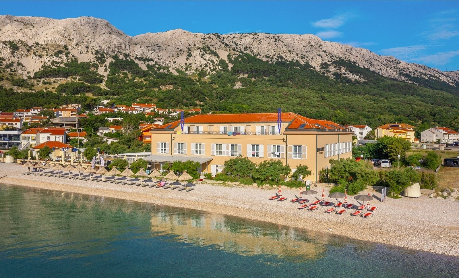 Un hotel sulla costa con vista sulle montagne, camere multiple e posizione direttamente sulla spiaggia.