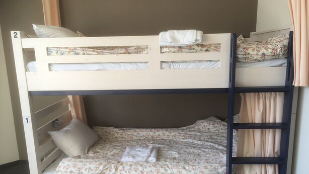 Een stapelbed met bloemenbeddengoed en een ladder.