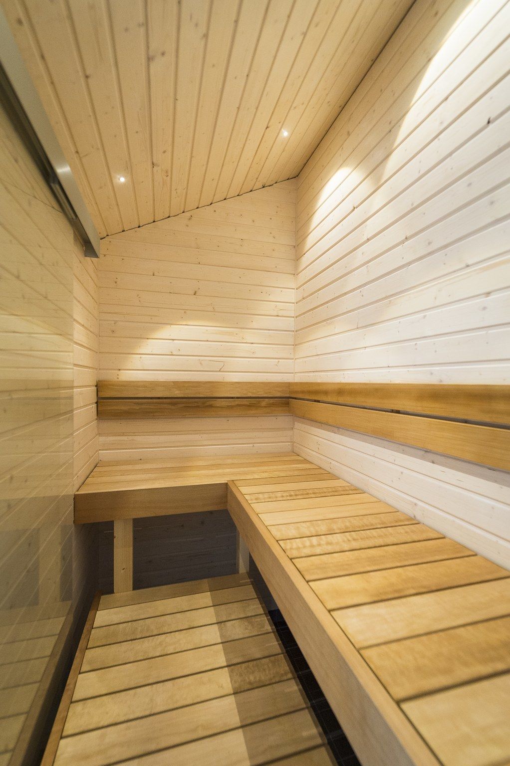 A sauna with wooden benches and a sloped floor.