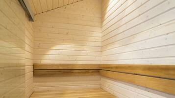A sauna with wooden benches and a sloped floor.