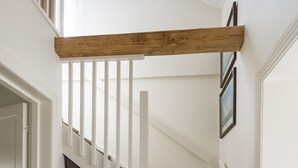 Un escalier avec des marches en bois et des rampes blanches, menant à l’étage supérieur.