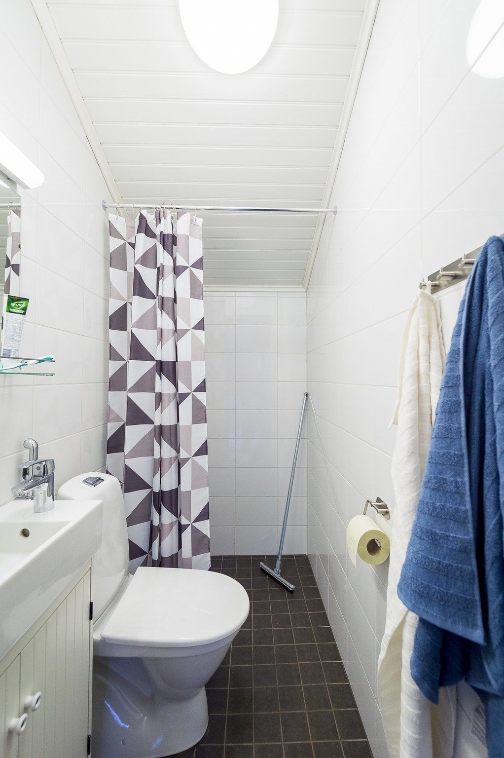 A bathroom with a toilet, sink, shower curtain, and towels.