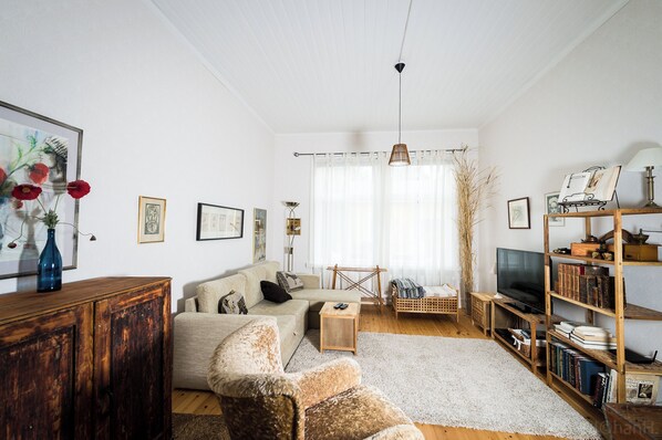 Una sala de estar con sofá, sillón, aparador de madera y mueble para televisor.