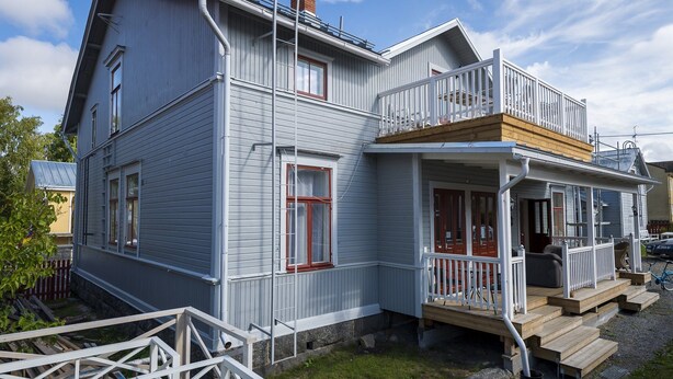 Une maison à deux étages avec un balcon, une véranda et une petite terrasse.