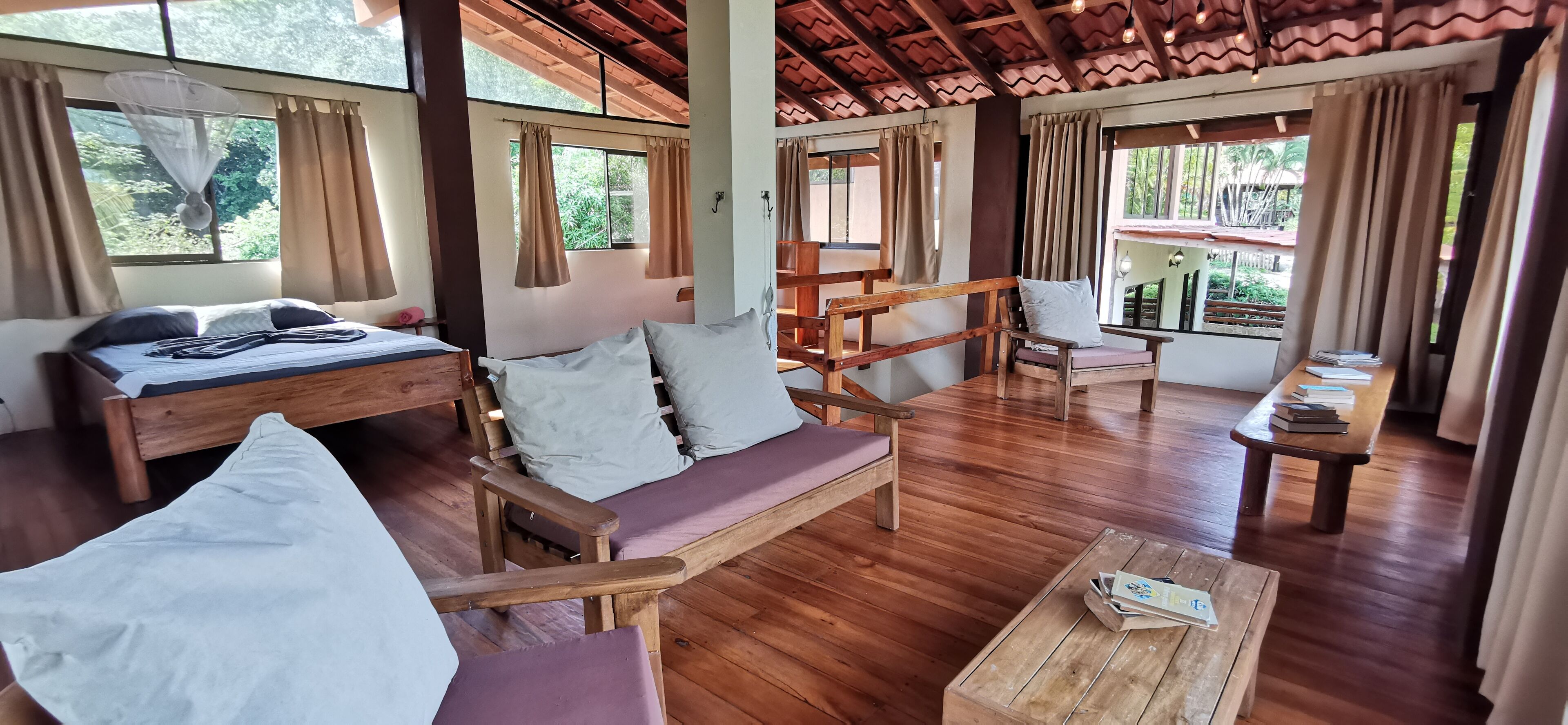 A wooden-floored room with a bed, sofa, and a small table.