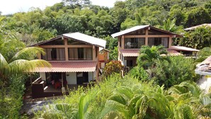 Un bungalow doté d’un toit en tuiles, entouré d’une végétation luxuriante et d’un petit jardin.