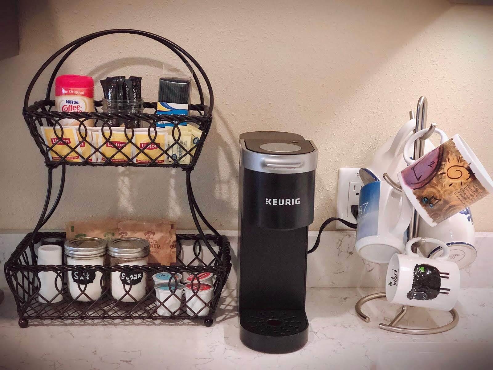 Un comptoir de cuisine avec une machine à café Keurig, un porte-épices et un porte-tasses contenant une tasse à thé.