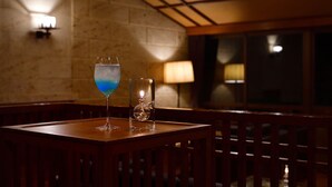 Una mesa con un vaso de líquido azul y una vela en un candelabro.