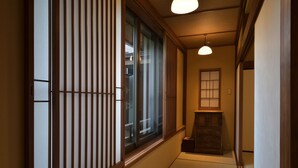 Un interior japonés tradicional con puertas correderas, suelo de tatami y un bajo mueble de madera.