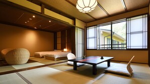 Una habitación japonesa tradicional con suelo de tatami, una mesa baja, un sofá y una cama.