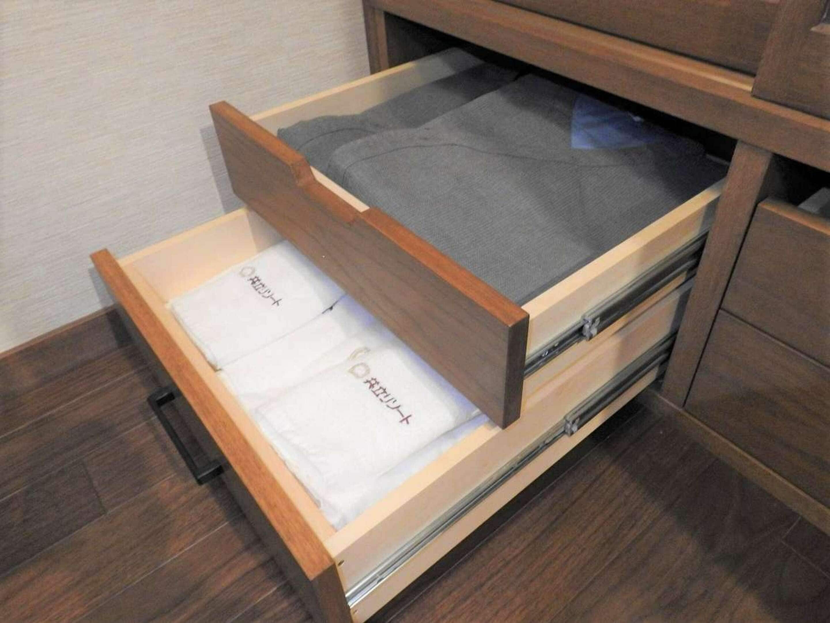 A wooden drawer with a grey fabric inside, a white cloth with text, and a metal handle.