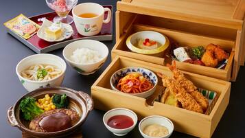 Un repas japonais traditionnel composé de différents plats, notamment du riz, des nouilles et des beignets de tempura, servis sur un plateau et dans une boîte en bois.