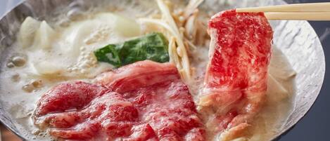 A hot pot with various ingredients, including meat and vegetables, being cooked in a broth.