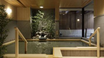 A traditional Japanese onsen with wooden railings, a rock garden, and a view of the outside.