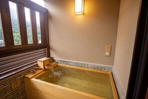 A wooden bathtub with a faucet, a window, and a wall-mounted light fixture. - Kotohira Onsen Onyado Shikishimakan (Kotohira)