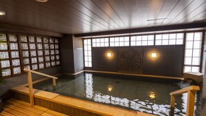 Ein traditionelles japanisches Onsen mit Holzbänken und einer Steinwand.