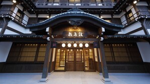 Ein traditionelles japanisches Gebäude mit Holzfassade, einem großen Eingang mit dekorativem Bogen und mehreren Fenstern.