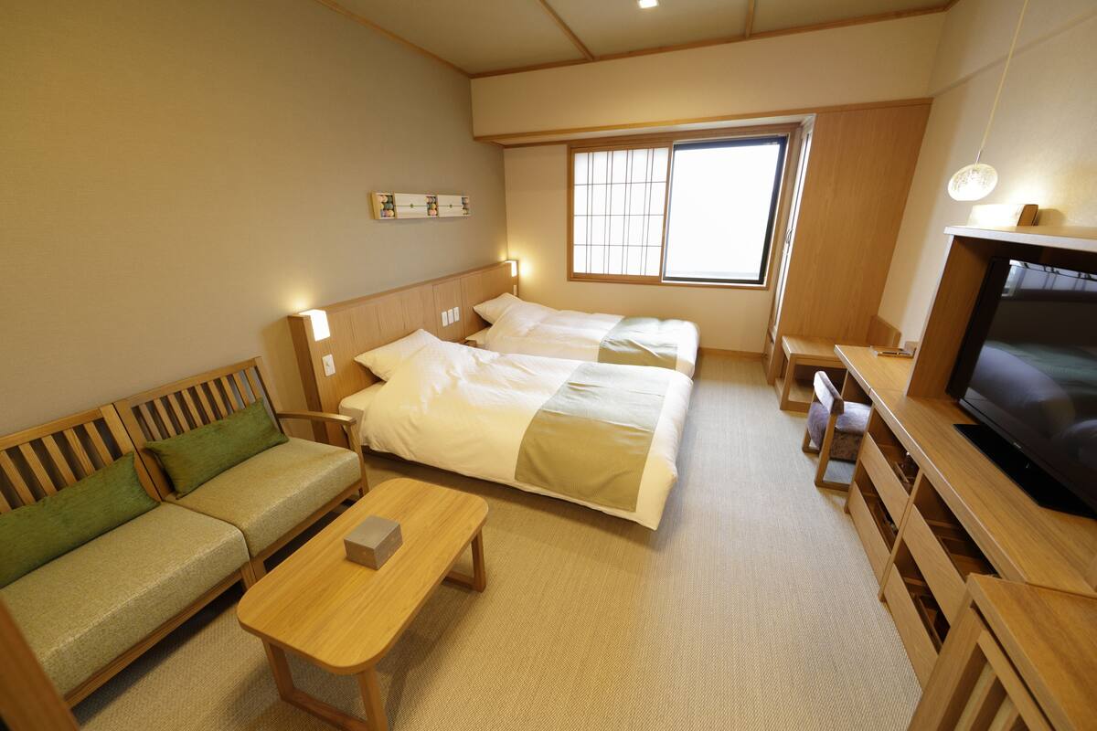 Une chambre d’hôtel avec un lit, un canapé, une télévision et une fenêtre.