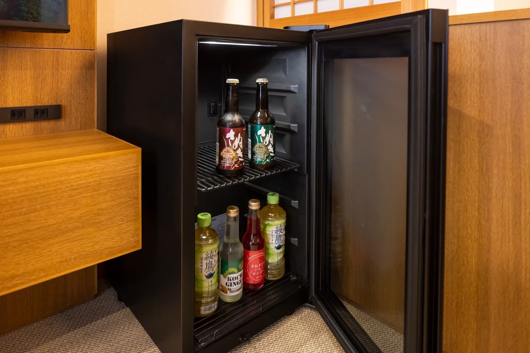 A compact refrigerator with multiple shelves, containing various bottles and a small appliance.
