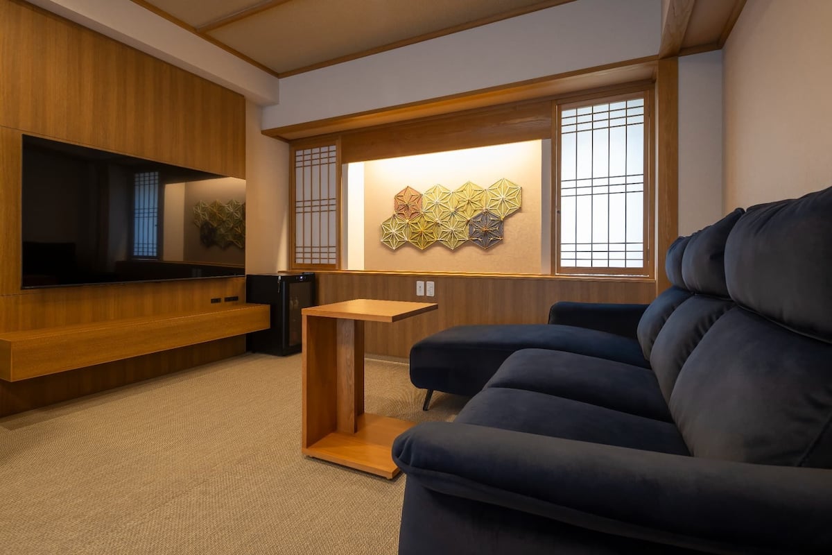 Un salon moderne avec un canapé bleu foncé, un meuble de rangement en bois et un élément décoratif mural.