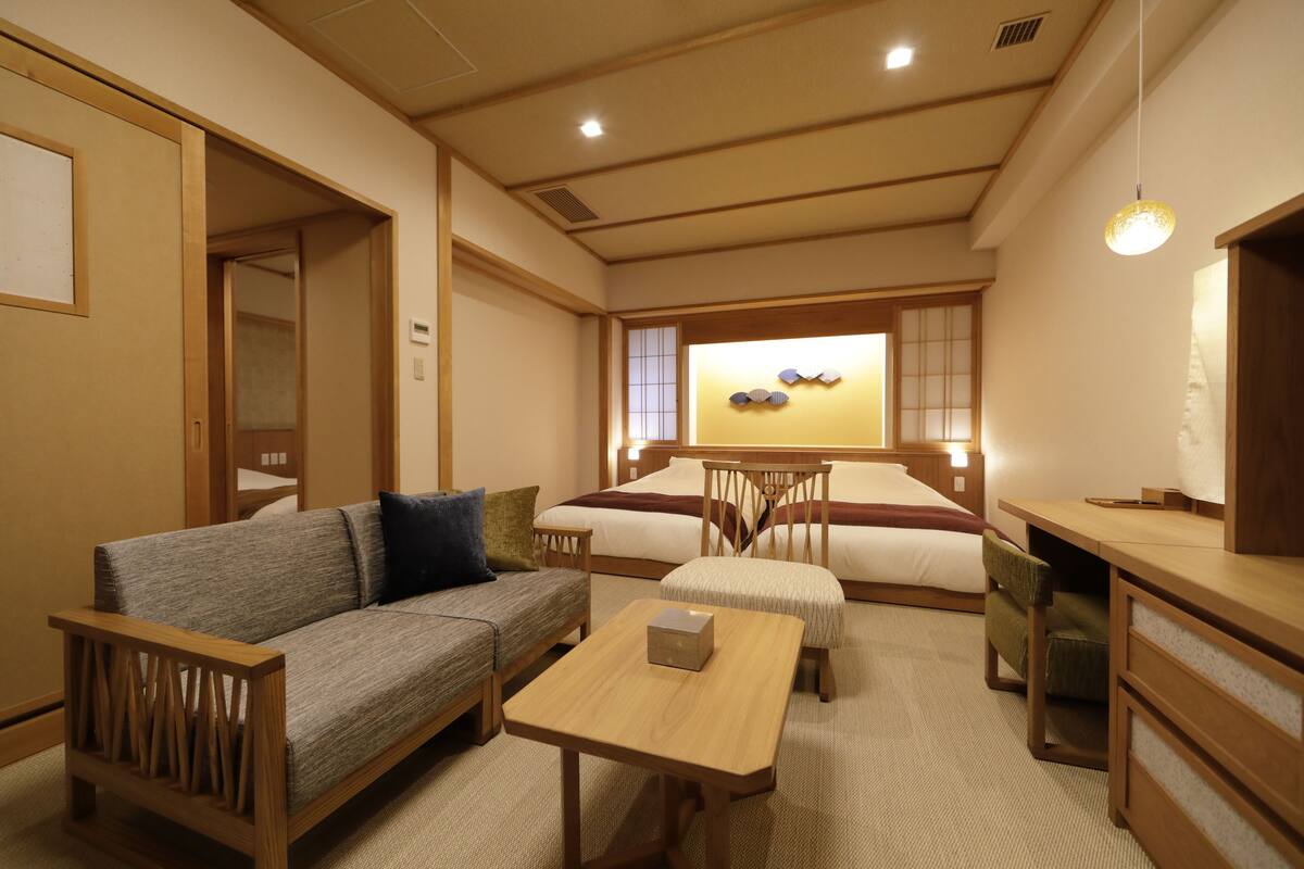 Une pièce de style japonais traditionnel, comprenant un canapé, une petite table, un lit et un bureau.