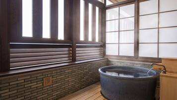 Una habitación tradicional japonesa con suelo de madera, un ventanal grande con puertas correderas tipo shoji y un balneario.
