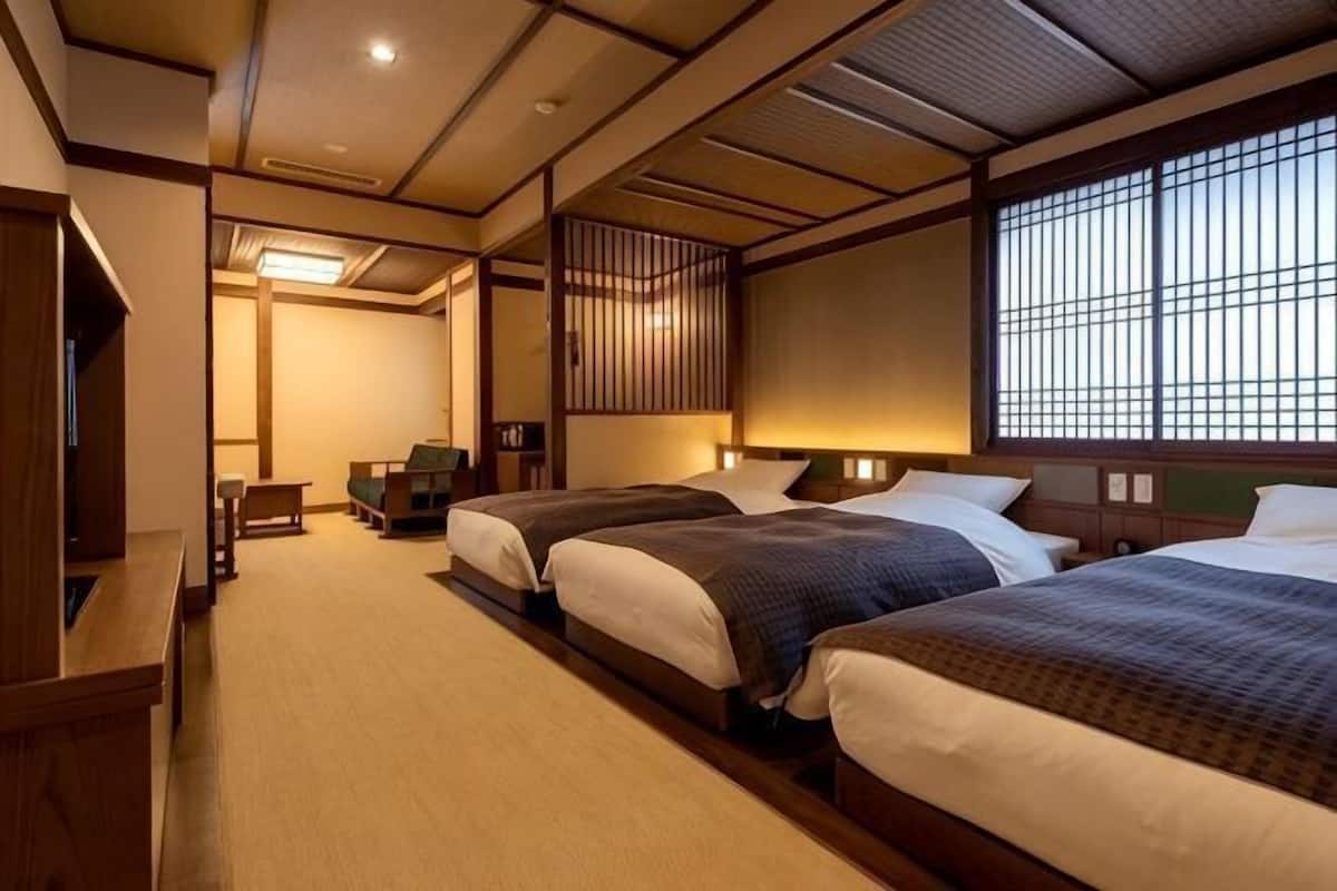 Une chambre d’hôtel de style japonais traditionnel, avec deux lits, un bureau et une vue sur la ville.