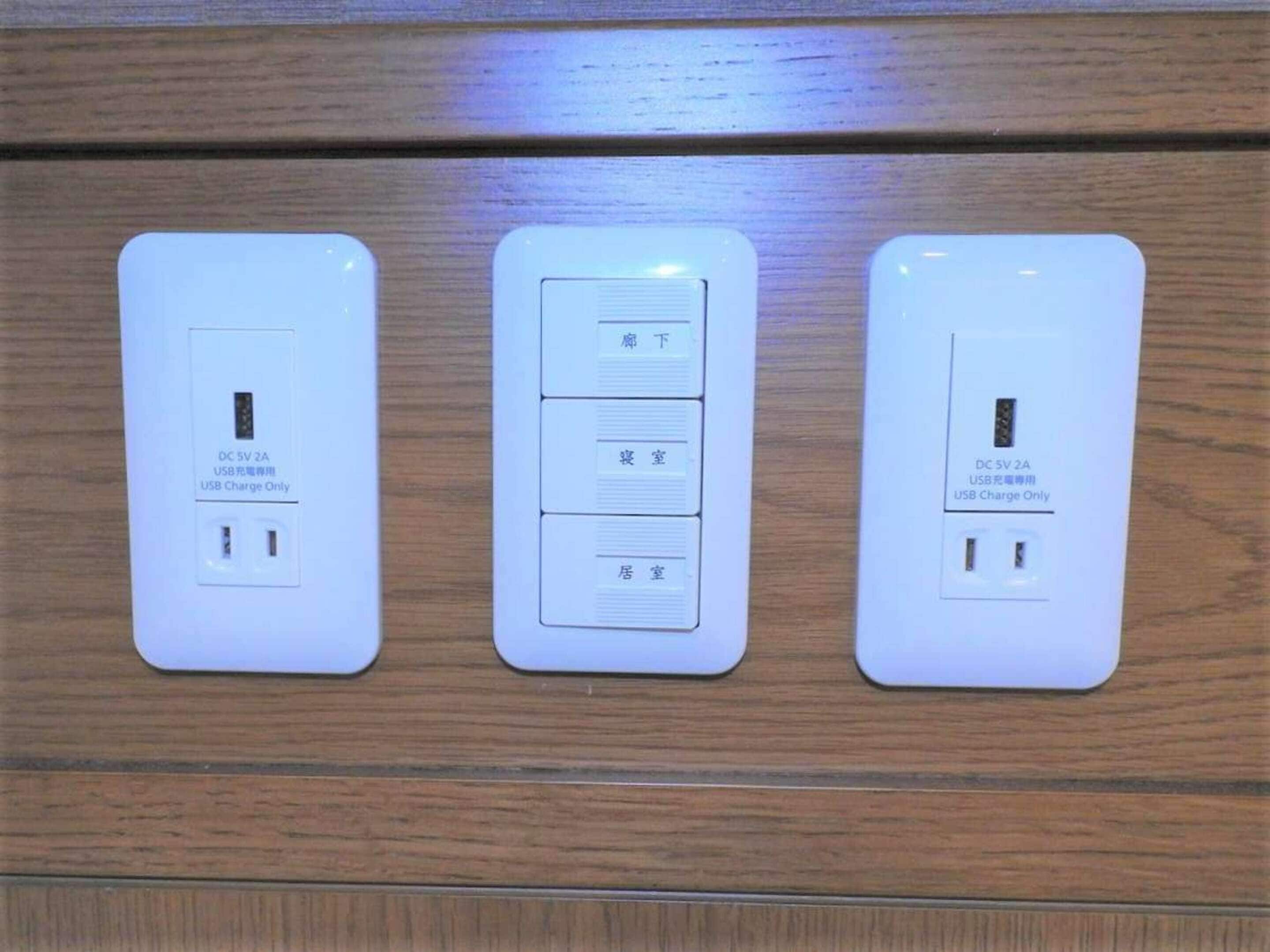 Trois prises électriques murales dotées de ports de chargement USB, avec des indications dans une langue étrangère.