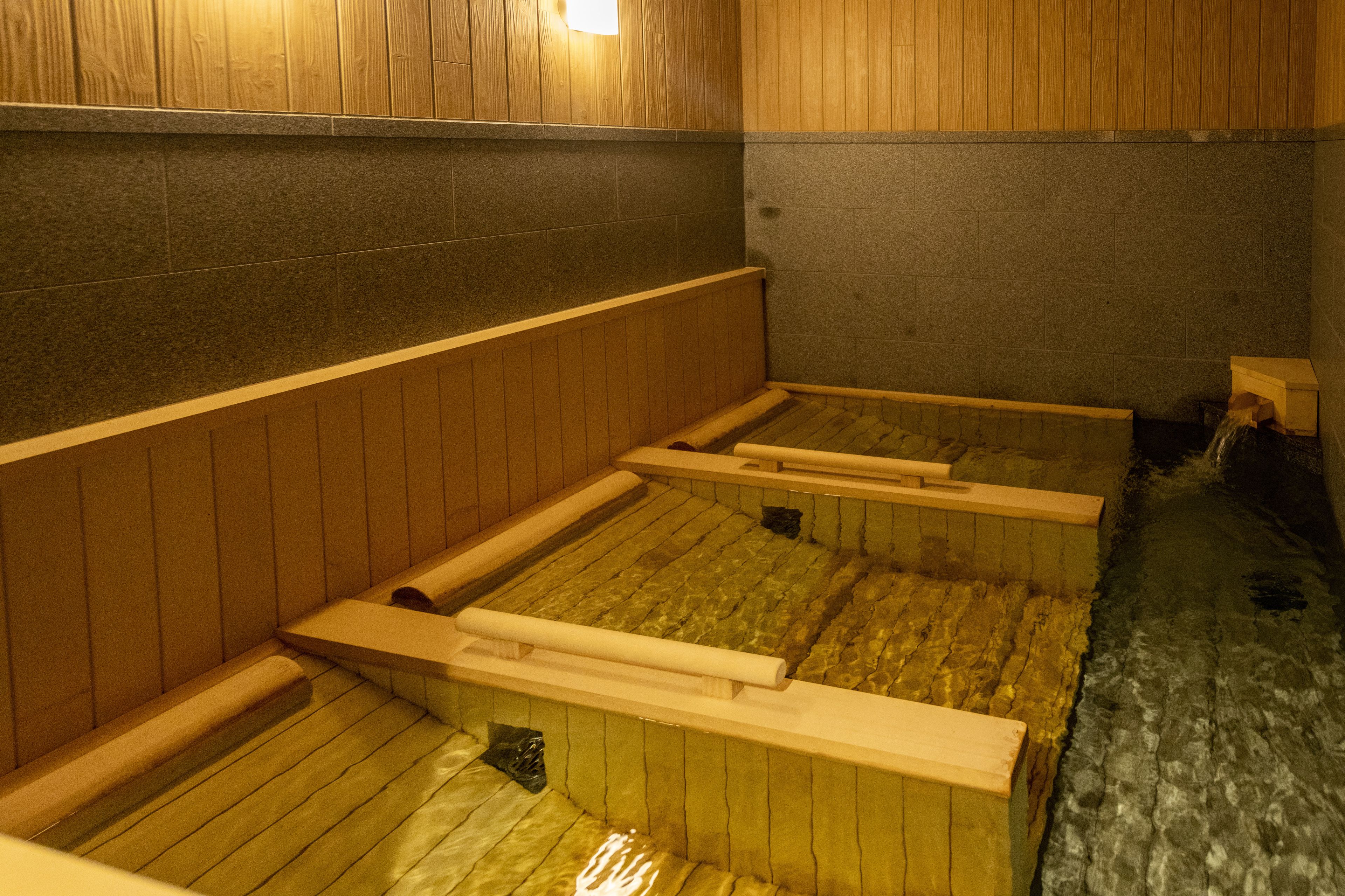 En traditionel japansk onsen med træbænke og stengulv.
