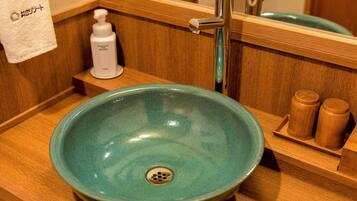 A bathroom with a teal ceramic sink, a wooden vanity, a mirror, and a towel rack.