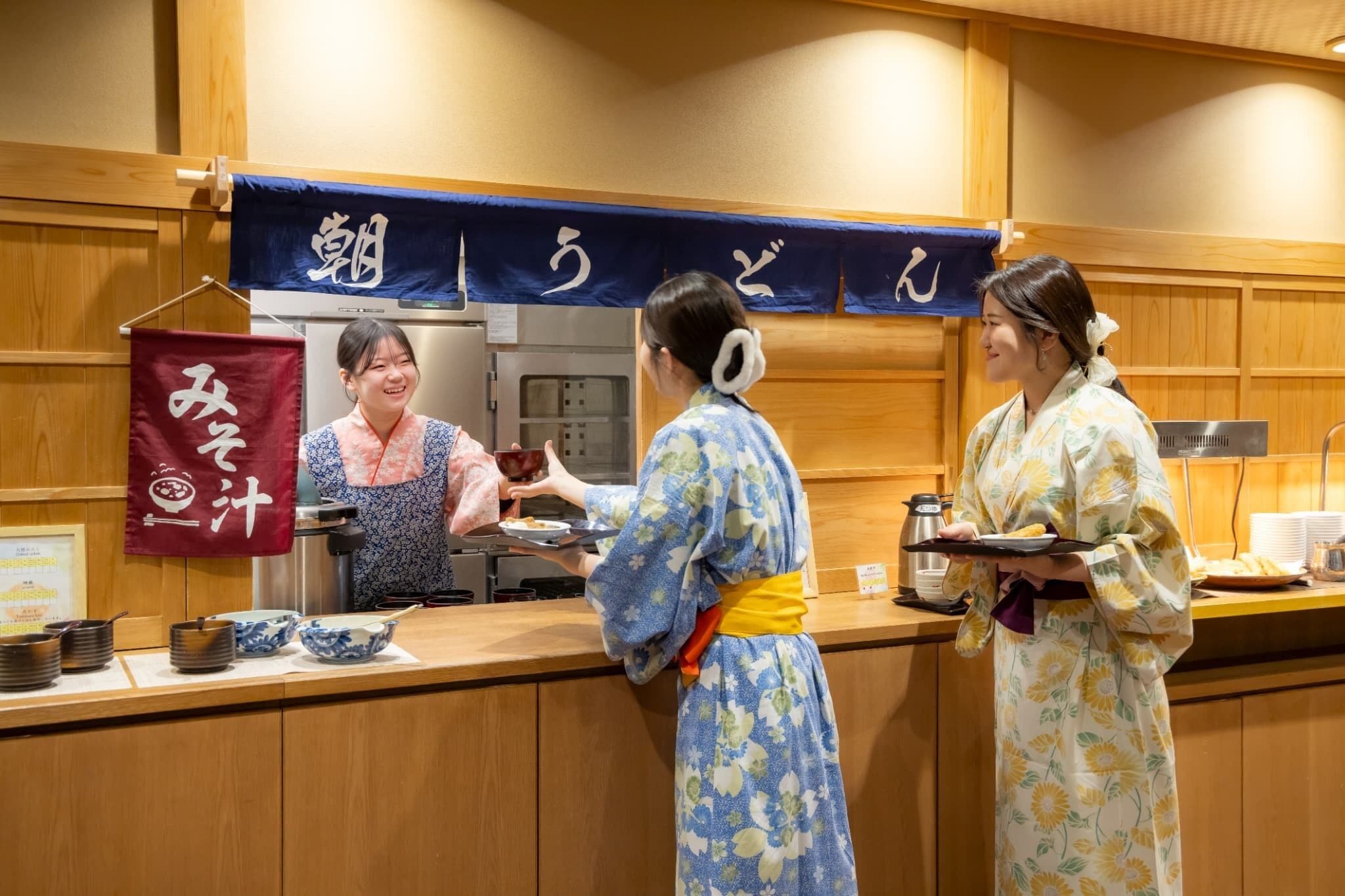 L’intérieur d’un restaurant japonais traditionnel, avec des lambris en bois et un comptoir où le personnel, vêtu de costumes traditionnels, sert les plats.