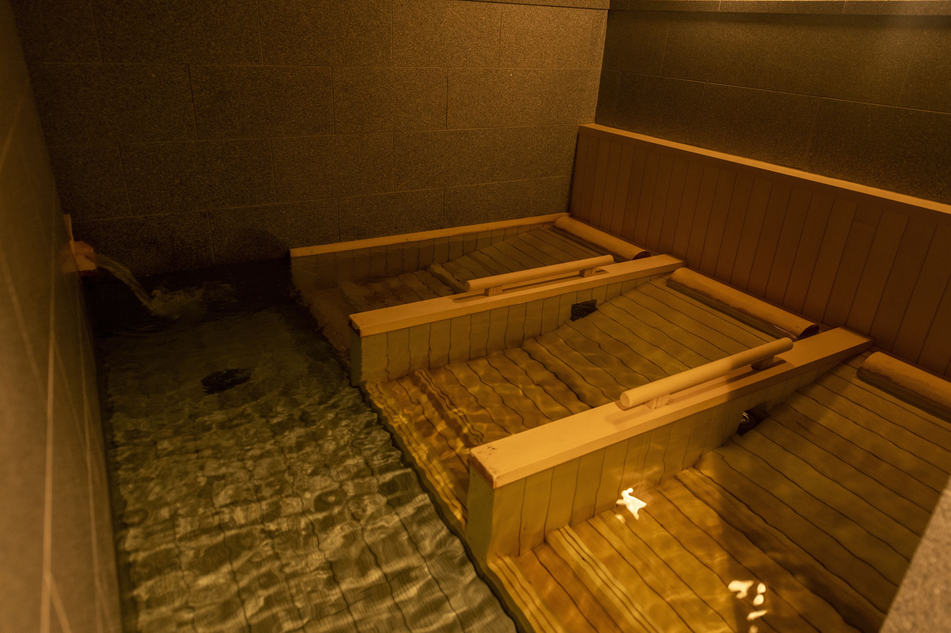 Un sauna avec des bancs en bois et un sol en pierre.