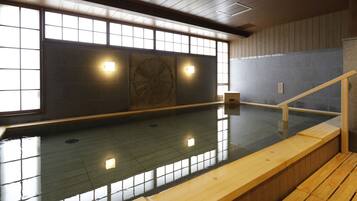 An indoor swimming pool with wooden benches and a tiled floor.