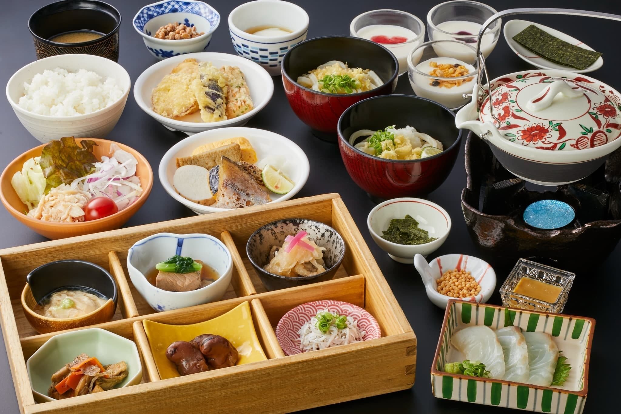 A variety of Japanese dishes arranged on a table, including rice, fish, and vegetables.