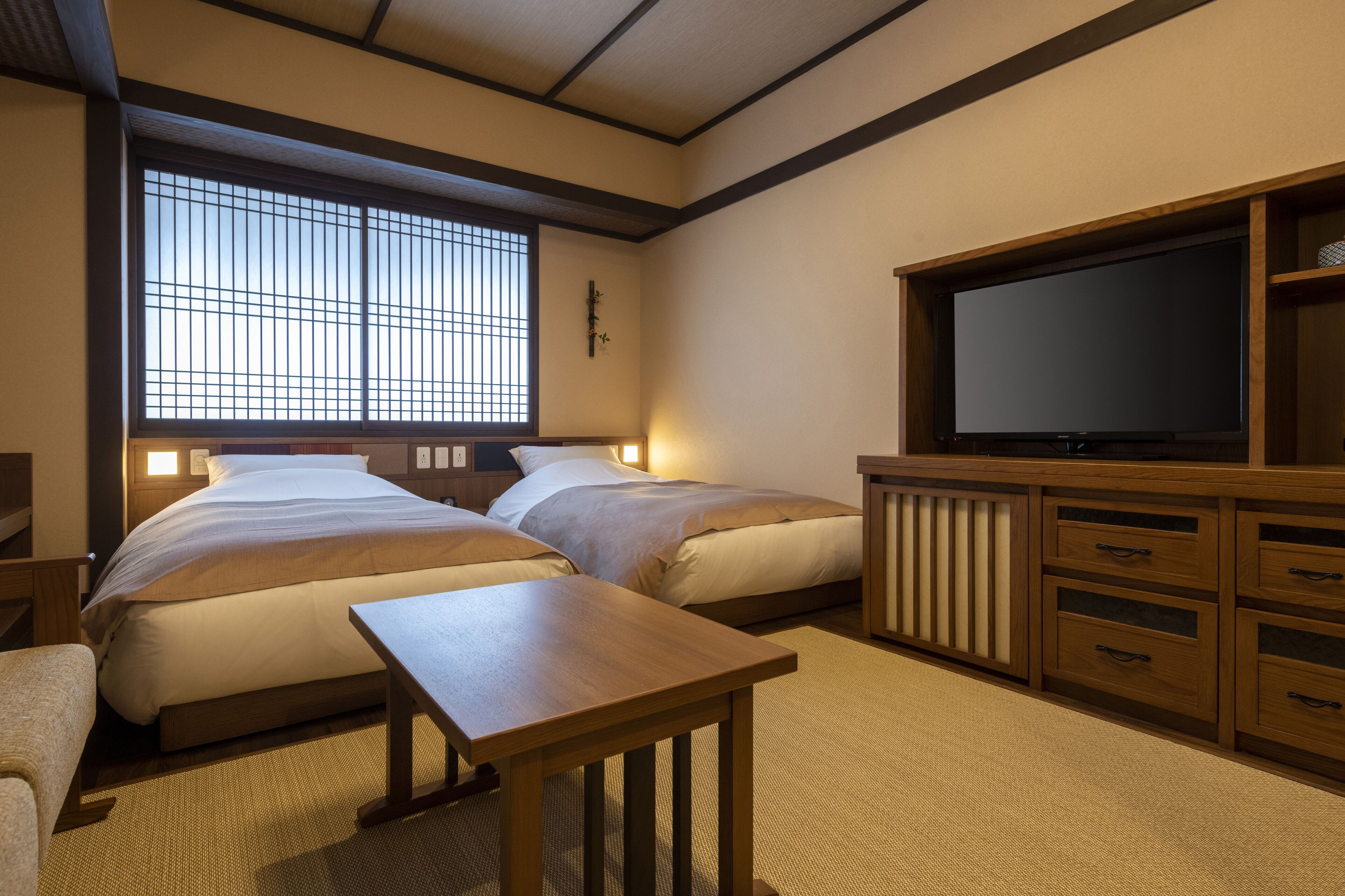 A traditional Japanese-style room with two beds, a television, and a wooden cabinet.