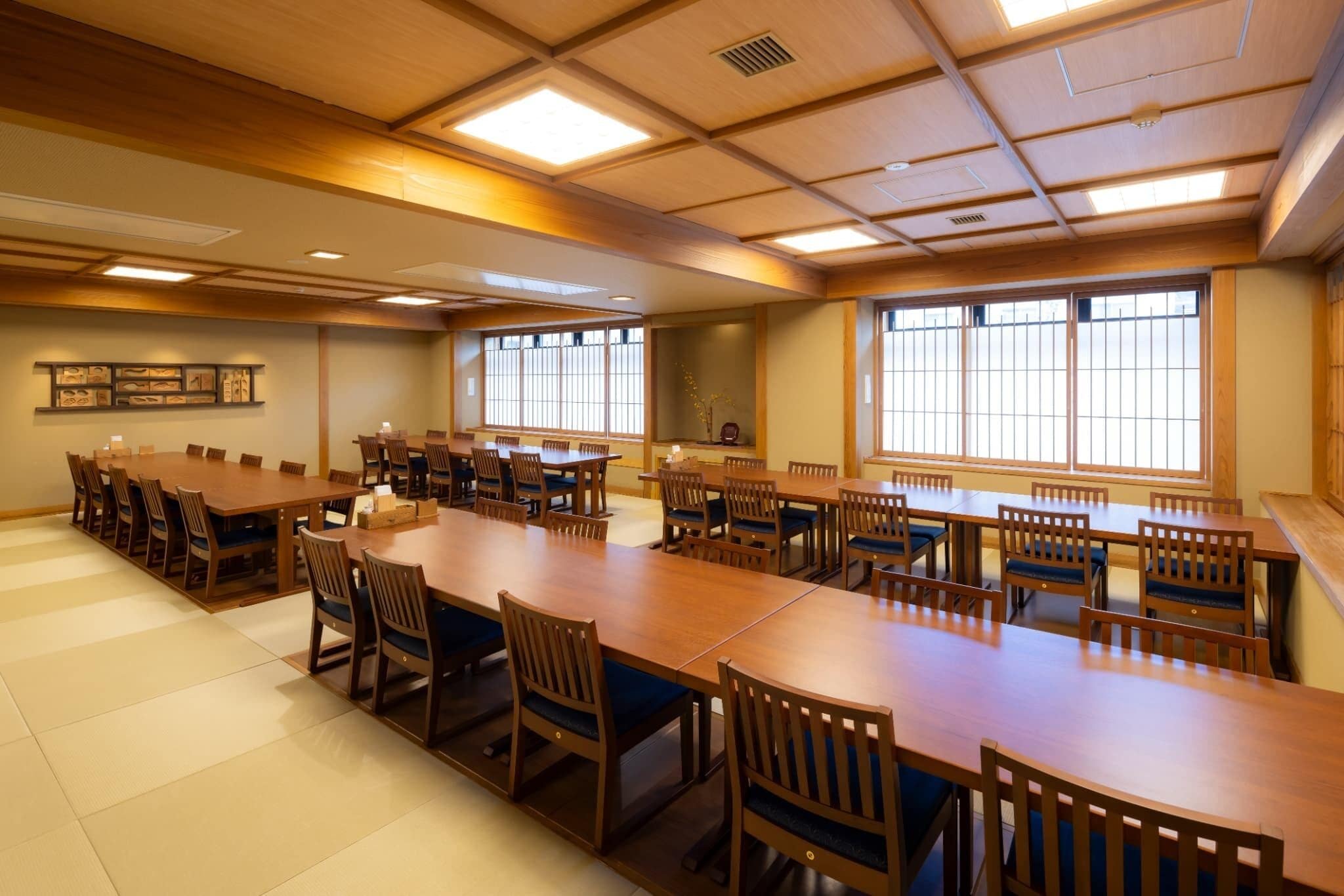 A conference room with multiple tables and chairs, large windows, and framed pictures on the walls.