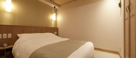 A neatly made bed in a hotel room with a wooden headboard, two wall-mounted lights, and a small bedside table.