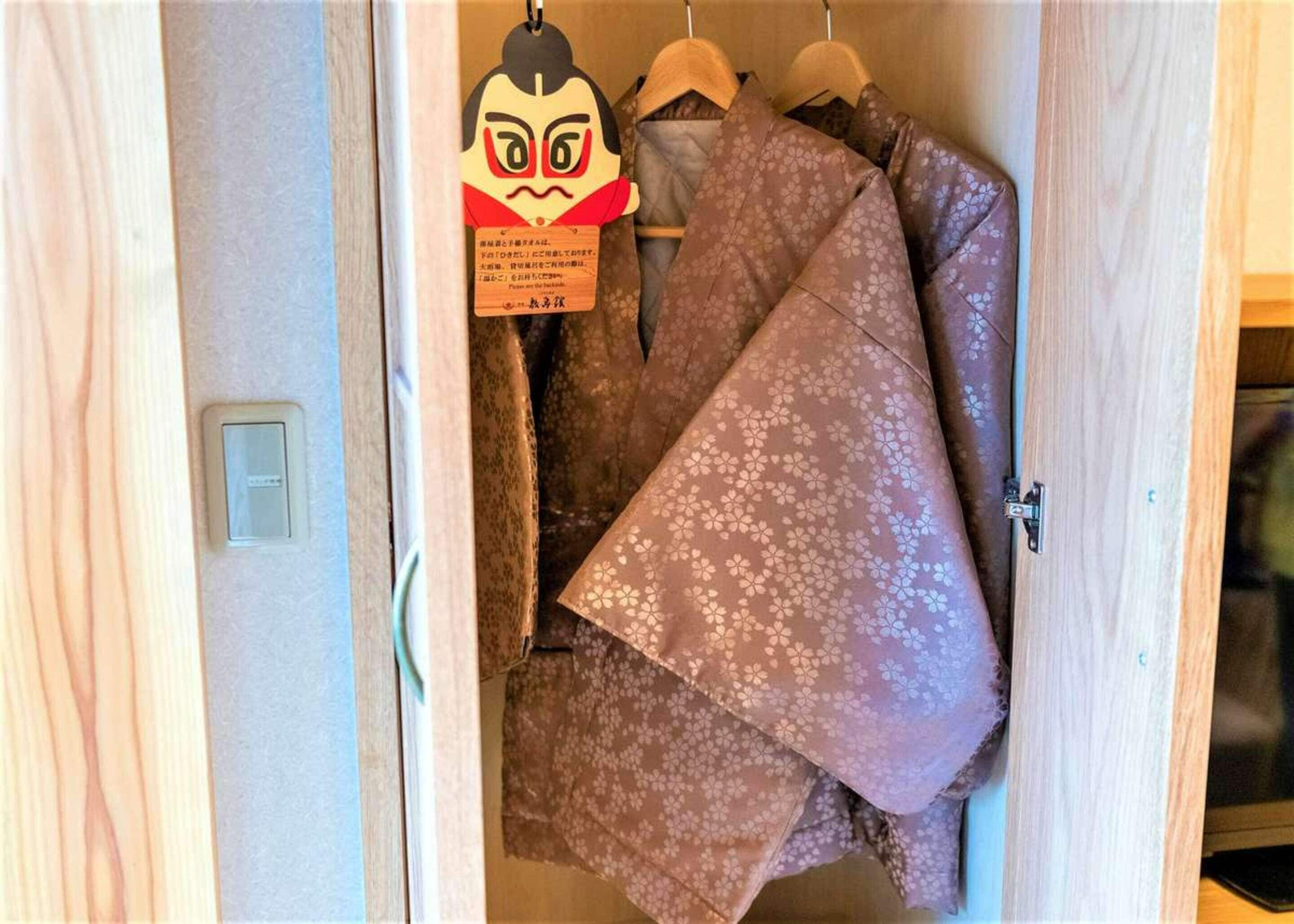 A wooden wardrobe with hanging clothes and a decorative item.