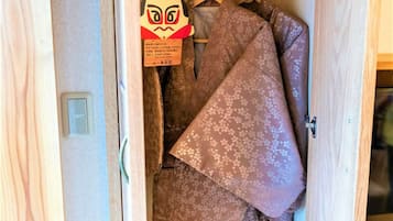 A wooden wardrobe with hanging clothes and a decorative item.