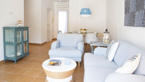 A living room with a sofa, armchairs, a small table with a book, and a wicker basket. - Apartment Can Serol 2 (Capdepera)