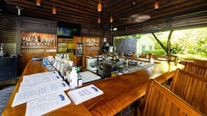 Un espace bar avec des meubles en bois, un comptoir où sont disposés les menus et une variété de bouteilles.