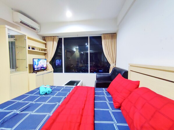 Une chambre d’hôtel avec un lit, une chaise, une télévision et une fenêtre donnant sur la ville.