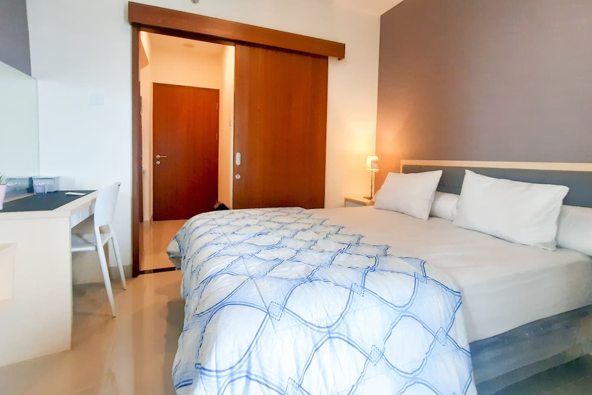 A hotel room with a bed, a desk, and a chair.